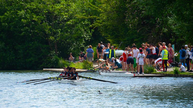 People cheering as a team rows down the Thames at Marlow Town Regatta
