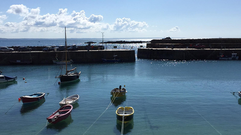 A view of boats in Mousehole's harbour with St Clement's Isle in the background