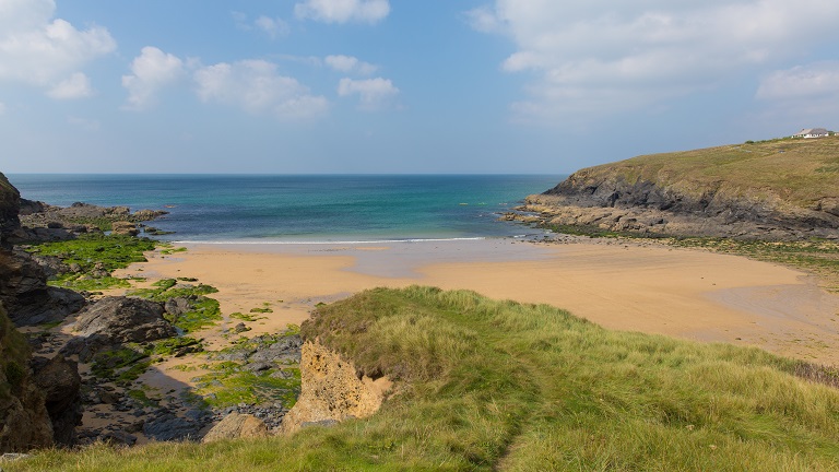 A view of an empty Poldhu Cove beach looking out to sea