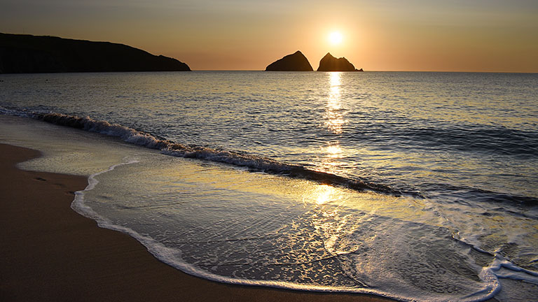 The twin rocks, or islands, of Gull Rocks at Holywell Bay in North Cornwall at sunset