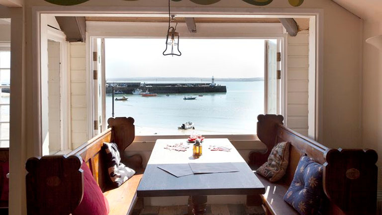 A table and chairs by the window at the Rum & Crab Shack with lovely sea and harbour views in St Ives
