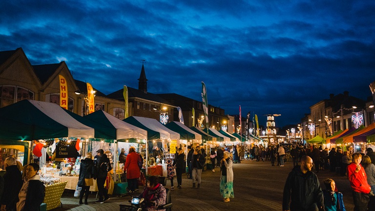 Truro Christmas Market in the late evening with Christmas lights and Christmas shoppers browsing market stalls