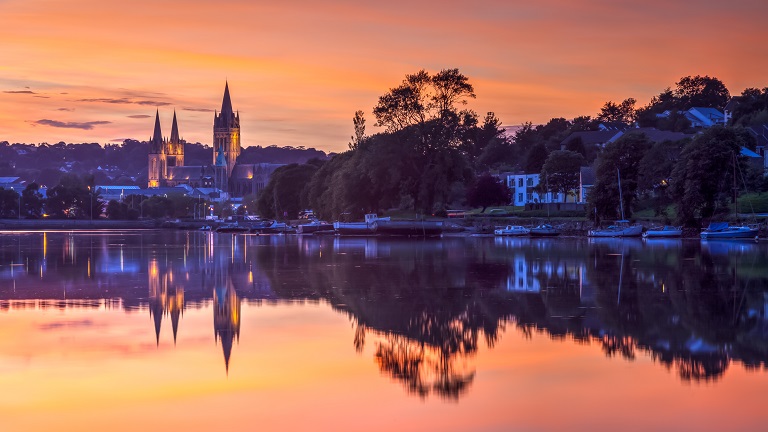 A picture of a beautiful sunset in Truro with an orange sky reflected in the flat-calm river