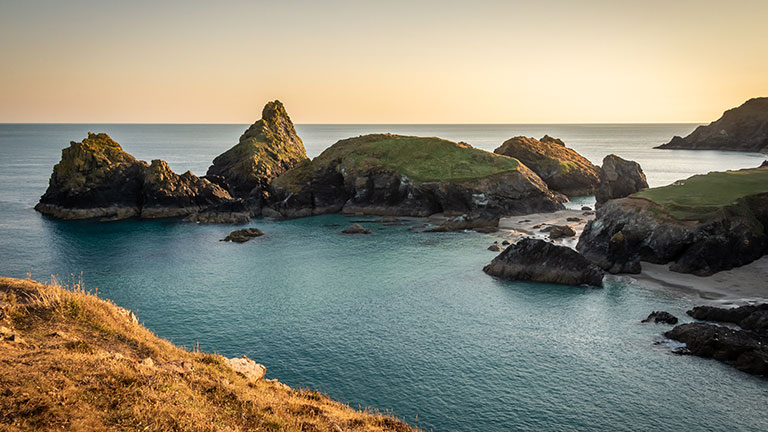 Looking out over the stunning coastal scenes of Kynance Cove at sunset