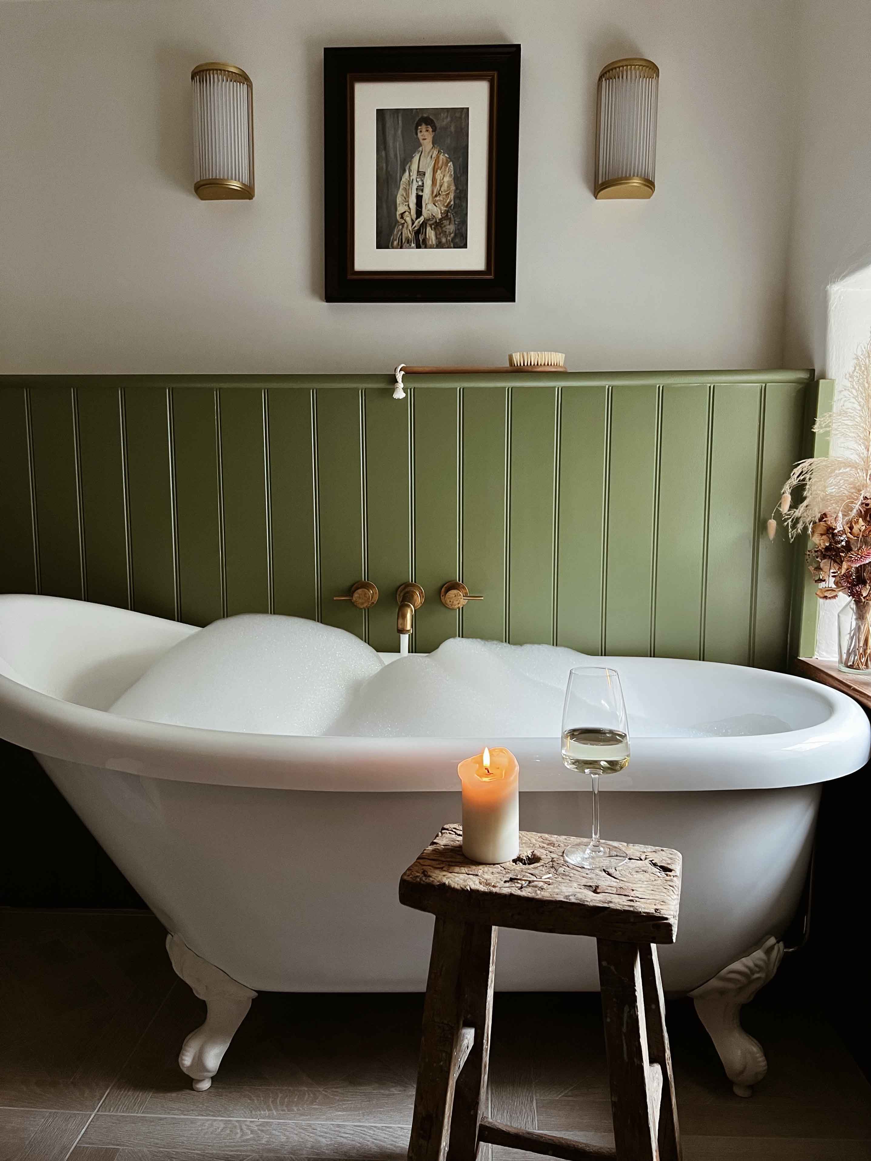 Bubble filled bathtub with candle and wine at Bramble Cottage