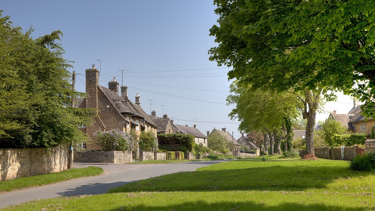 An attractive village with trees, surrounded by the pretty cottages of the village of Kingham in the Oxfordshire Cotswolds