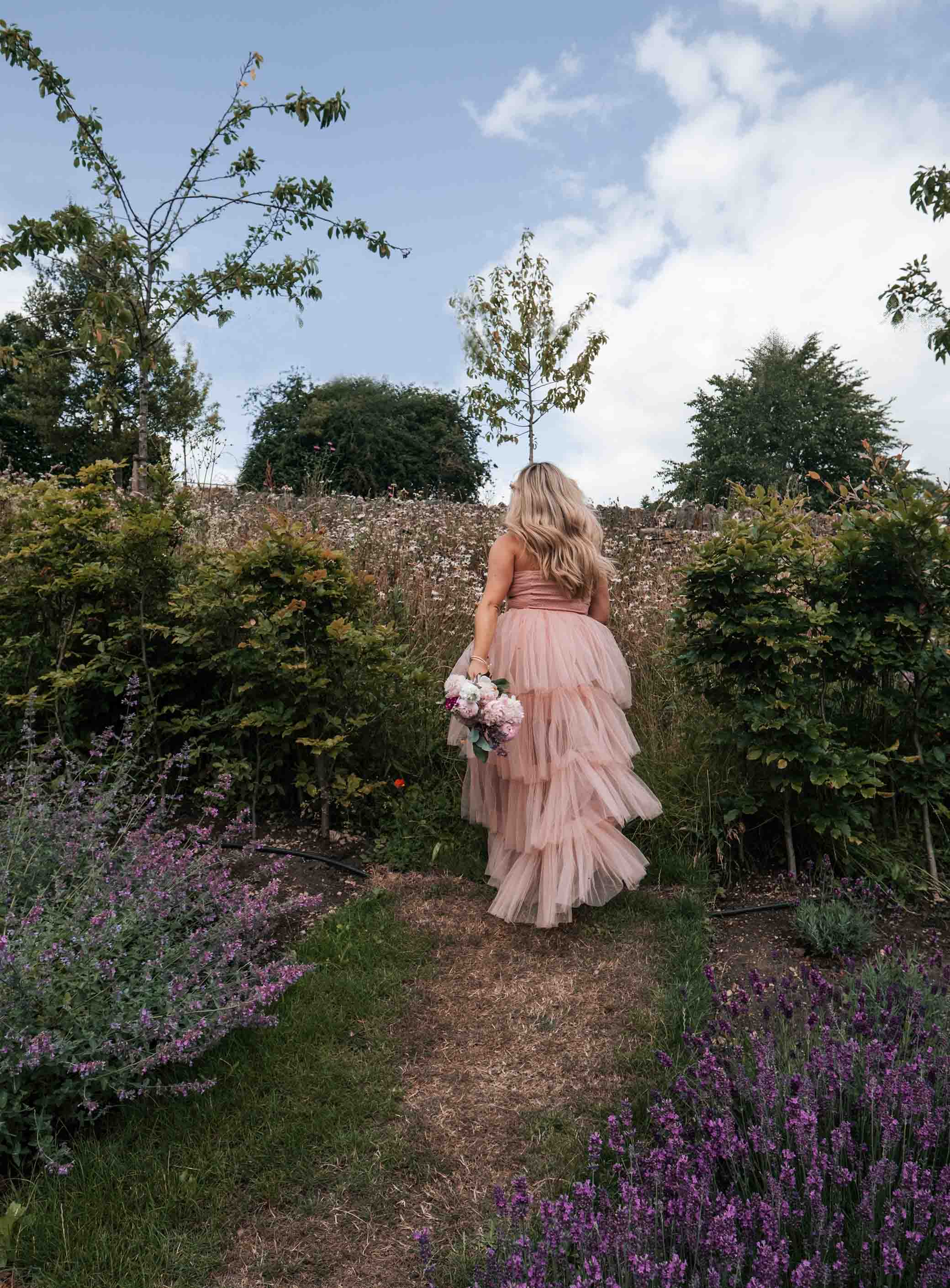 A lady enswathed in a pink dress walking through lavender gardens