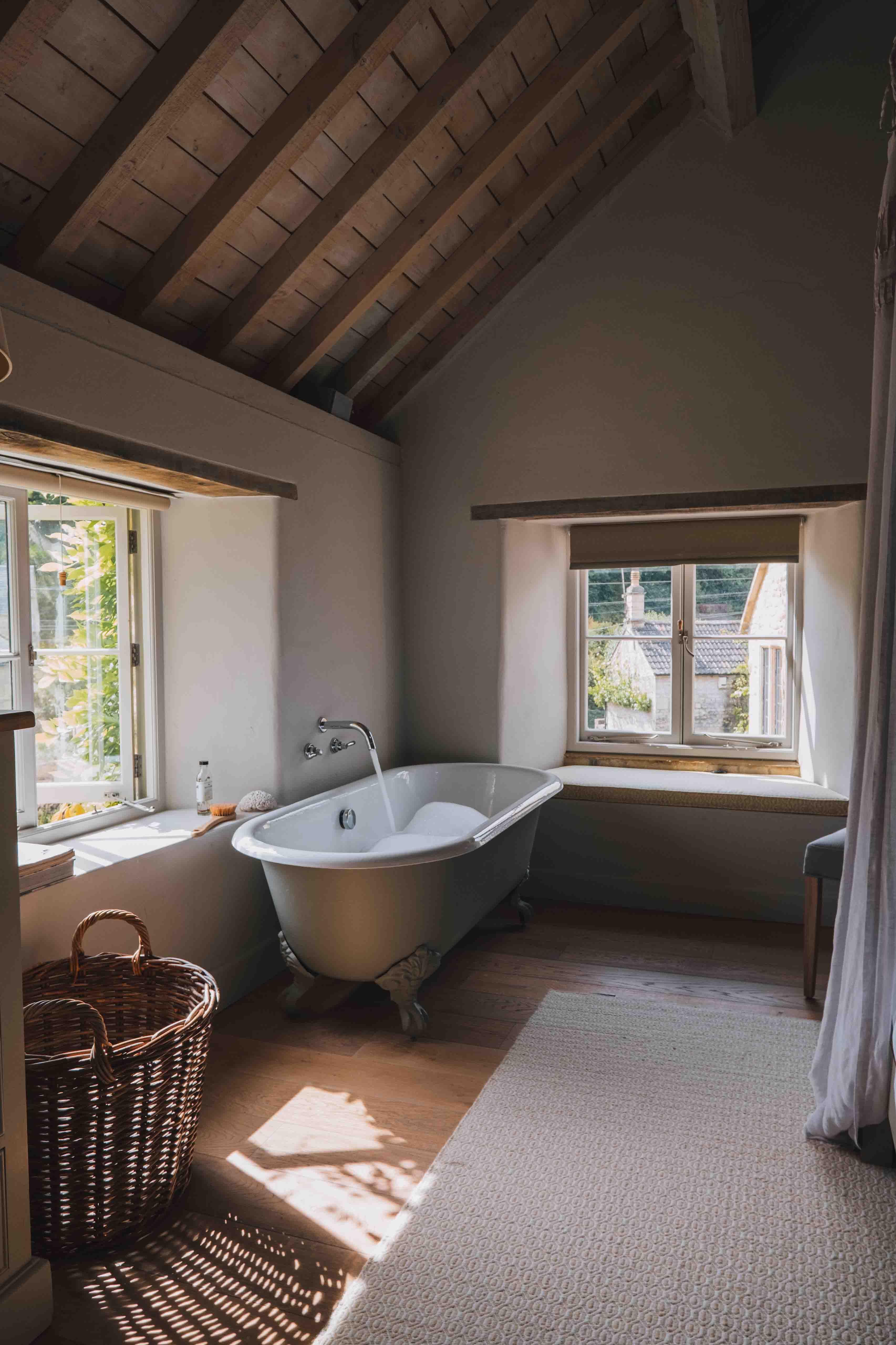 A running bath topped with bubbles and situated next to a garden-view window at Lavender