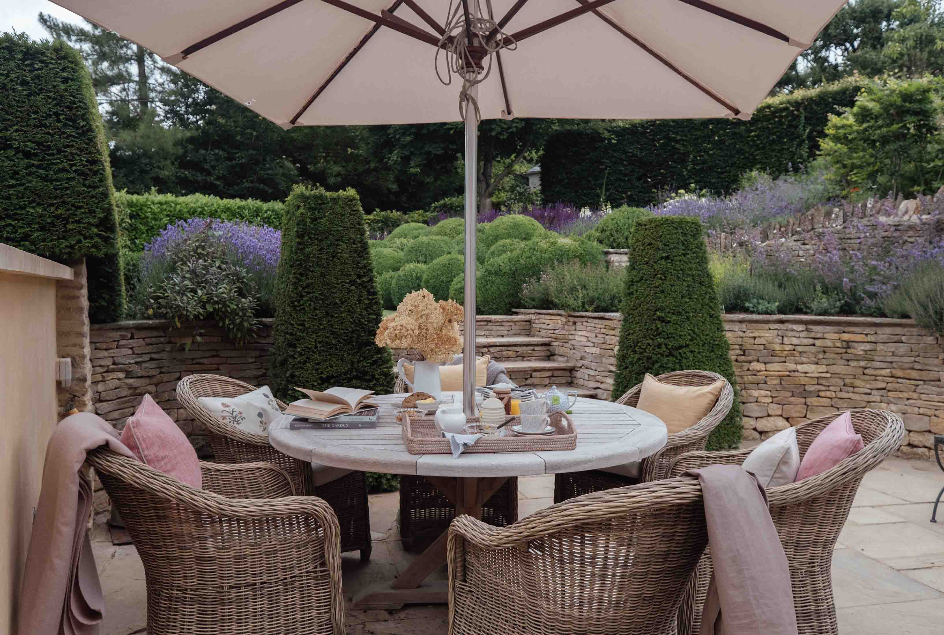 A picturesque garden arrangement at Lavender with an outdoor table and chairs shaded by a pretty parasol