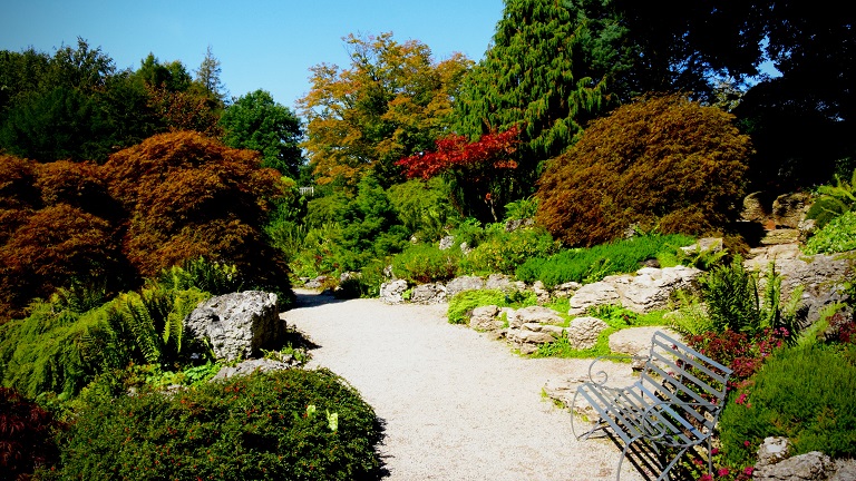 A path leading through the trees, shrubs and planted borders at Sizergh Castle in the Lake District