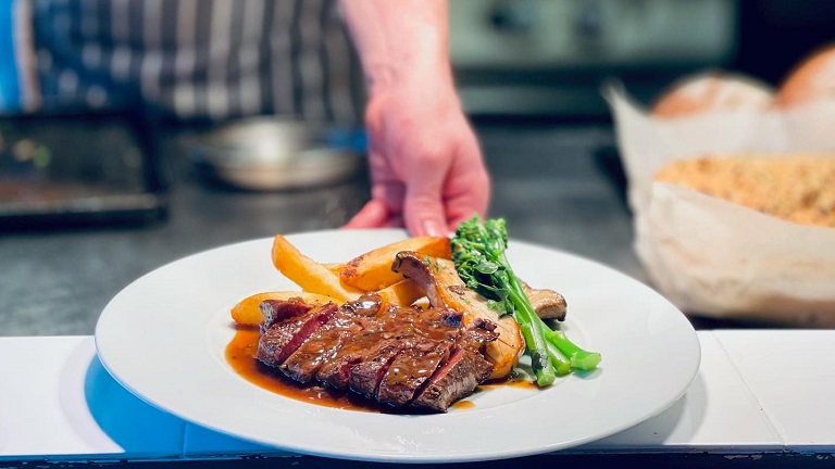 A plate of cooked steak, chips and broccoli drizzled in jus, served by one of the chefs at Four and Twenty in Penrith