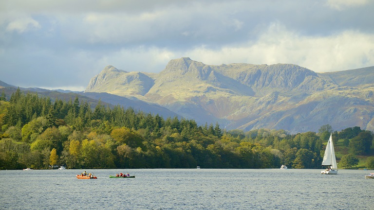 A sailing boat on Lake Windermere with Langdale Pikes behind