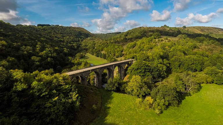 A view of Bakewell Bridge crossing over a wooded valley in the Peak District National Park in Derbyshire