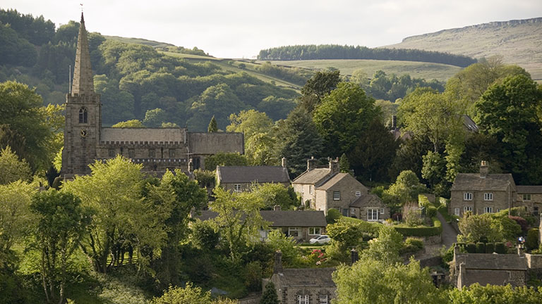 Houses and the local church through the trees in the pretty village of Hathersage in the Derbyshire Peak District