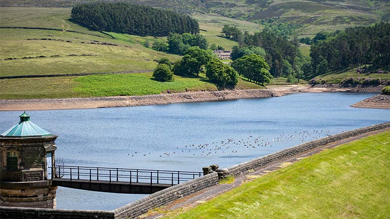 The peaceful waters of Kinder Reservoir backed by rolling fields