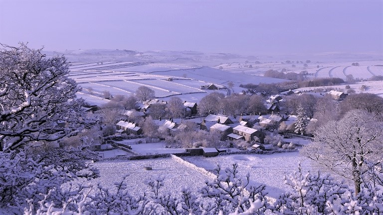 A snowy Derbyshire village surrounding by snow covered fields in winter