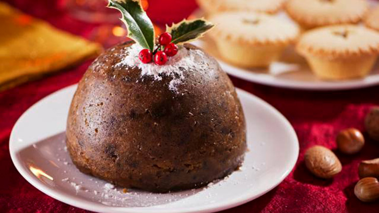 A Christmas pudding topped with cranberries and icing sugar