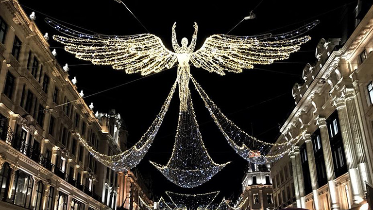 A beautiful illuminated angel soaring above Christmas streets