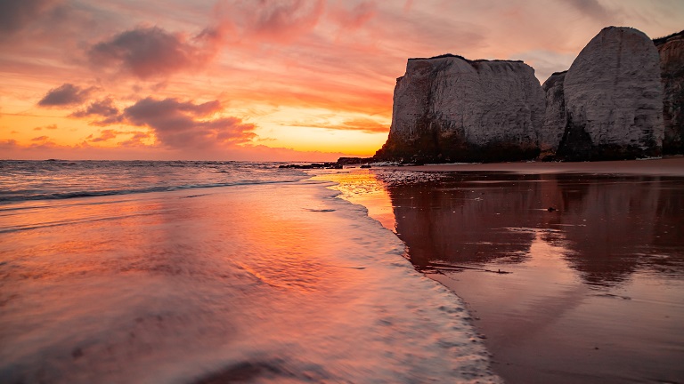 A view of Botany Bay in Kent at sunset with a gentle sea lapping the shore