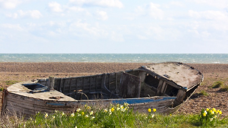 An old boat on the pebbly shore of Dingle Beach in Kent - said to be England's only desert