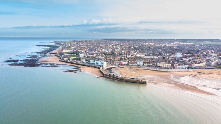 A view of the famous Margate Beach in Kent with the town in background and the beach and harbour in the foreground