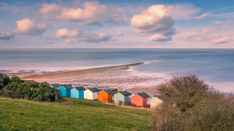Tankerton Beach in Kent towards sunset with multi-coloured beach huts and "the Street" in view