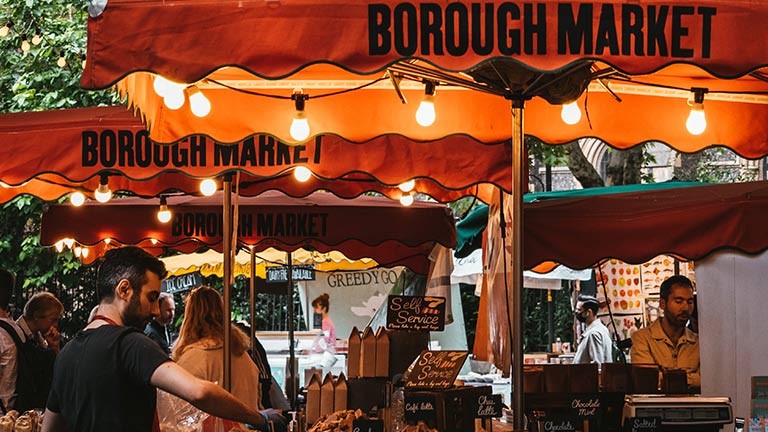 Food stalls at Borough Market with big orange parasols and lights