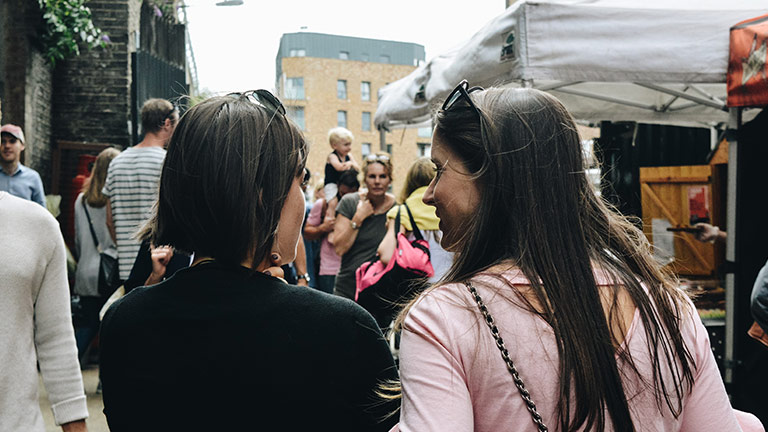 Two women walking down a busy market street in London