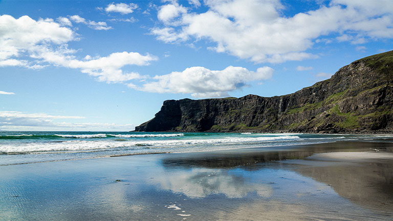 The sandy beach and towering cliffs at Talisker Bay on the Isle of Skye