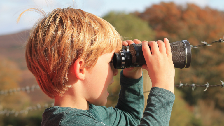 Young child holding up binoculars while birdwatching on Exmoor 