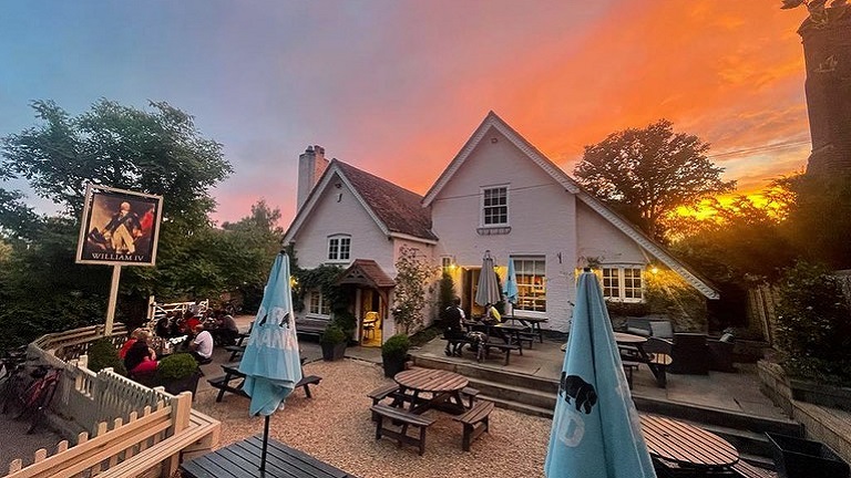 A sunset colouring the sky behind The William IV pub near Albury