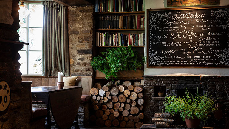 The specials board, a window table, and chopped logs ready for the fireplace inside the Black Swan restaurant in Oldstead, York