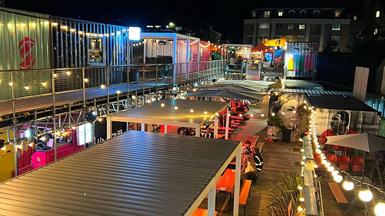 The outdoor food court at Spark York in the nighttime, illuminated by multi-coloured lights