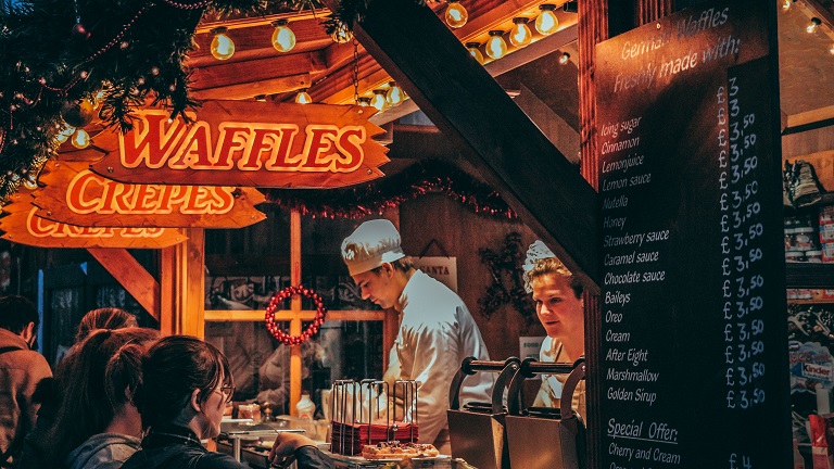 A Christmas market stall selling delicious treats including waffles and crepes