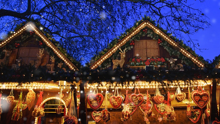 Christmas treats and fairy lights hung from wooden chalets at a Christmas market