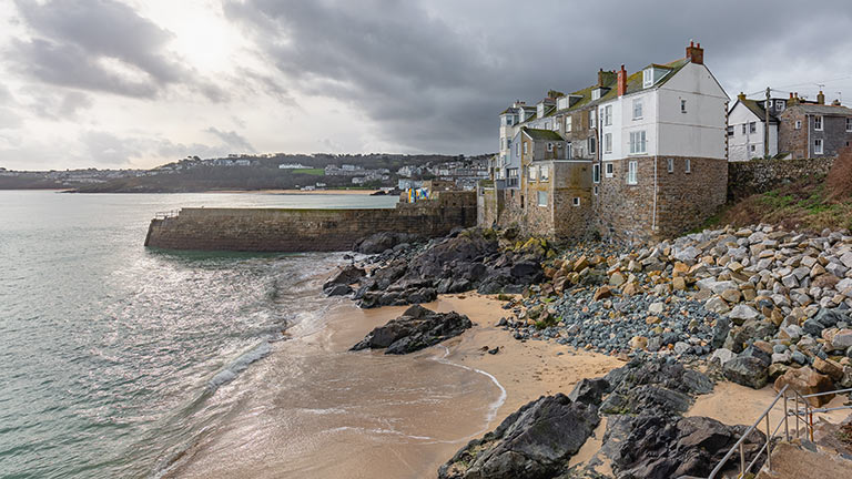 A little harbour beach with golden sand and backed by rocks and cottages