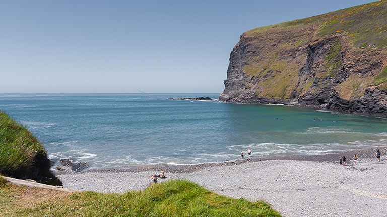 Towering cliffs loom over the pretty beach at Crackington Haven in Cornwall