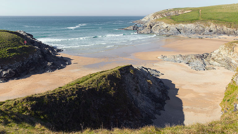 Golden sands and rugged cliff formations at Polly Joke beach in Cornwall