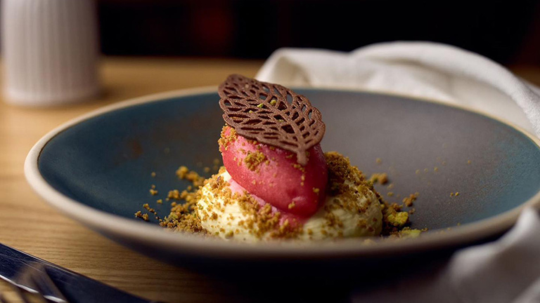 An expertly crafted dessert dish topped with a chocolate leaf served by The Mulberry in Falmouth