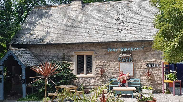 The sunny exterior of Holy Mackerel Cafe in Helford village, Cornwall