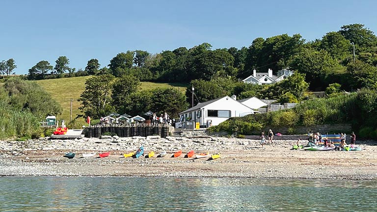 A view from the sea of Talland Bay Beach Cafe on a sunny day
