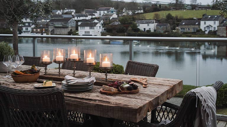 Candles and dinner plates on a wooden table that overlooks the beautiful river in Fowey