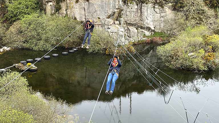 People zip lining on the Zip Wire Safari at Via Ferrata in Cornwall