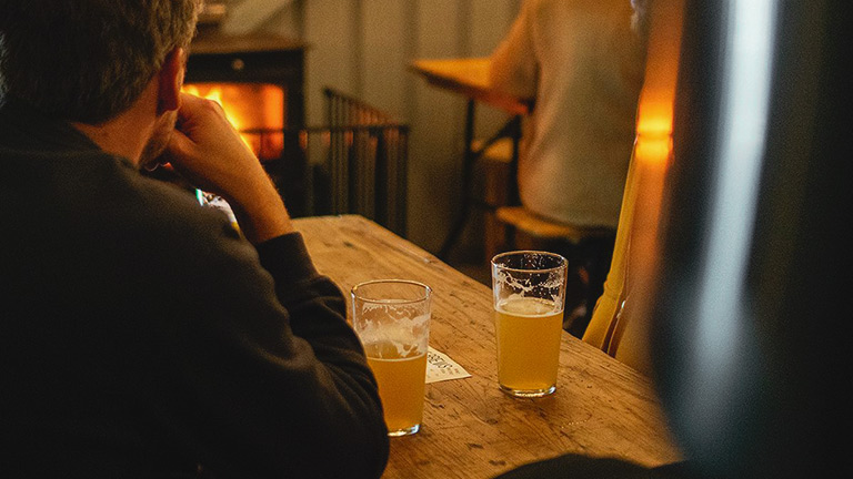 Pints of signature ale being enjoyed in front of a crackling fire at Pipeline Brewing Co