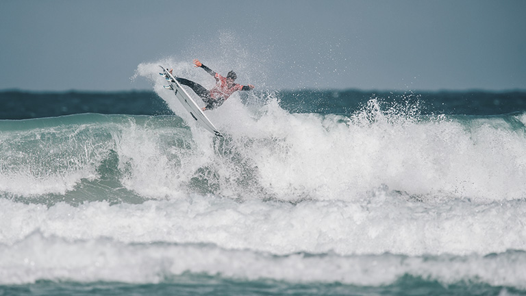A surfer riding the waves during a competition at Boardmasters Surf and Music Festival in Newquay