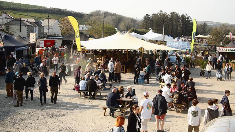 Crowds mingling together in front of food stalls at Porthleven Food Festival