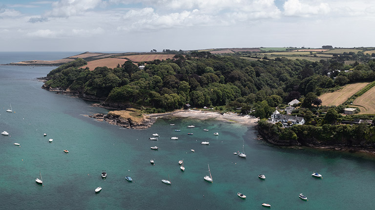 An aerial view of Gillan and the Helford River with sailing boats on moorings
