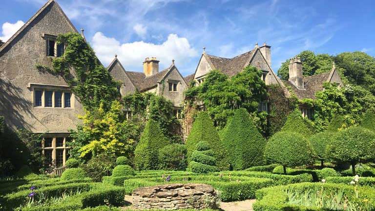 The beautiful golden stone house and topiaries at Abbey House Manor and Gardens in the Cotswolds