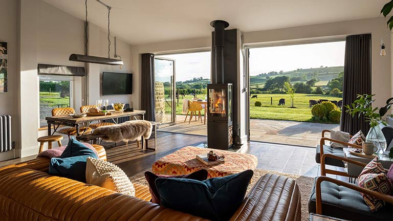 A beautiful living room looking over a verdent garden and rolling hills in the Cotswolds