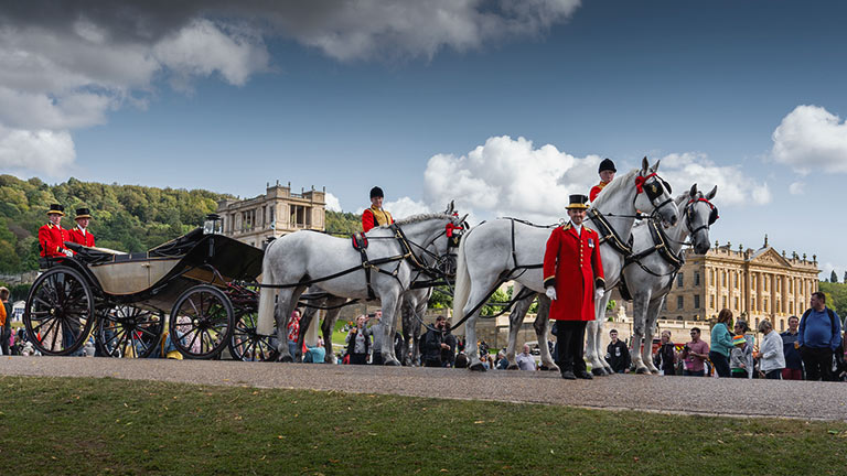 Horses and their suited guard handlers in royal livery at Chatsworth Country Fair